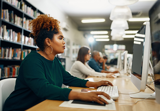 Row of people using computers at a library.